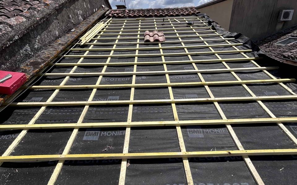 Écran sous toiture neuf, contre-liteaux et liteaux en bois posés sur toute la pente, avant la pose des tuiles canal