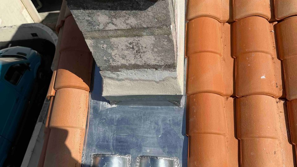 Solin en zinc soudé autour d'une souche de cheminée, entouré de tuiles canal neuves