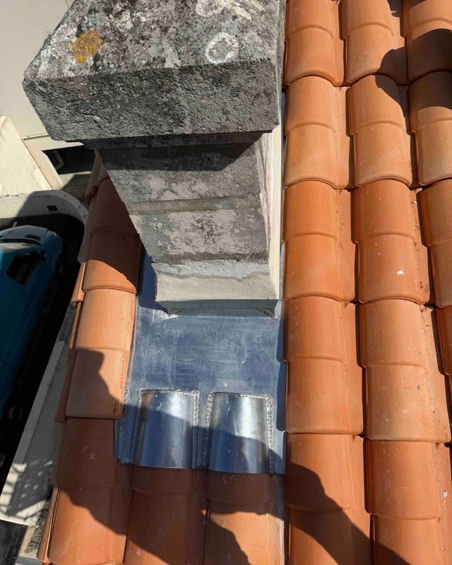 Solin en zinc soudé autour d'une souche de cheminée, entouré de tuiles canal neuves