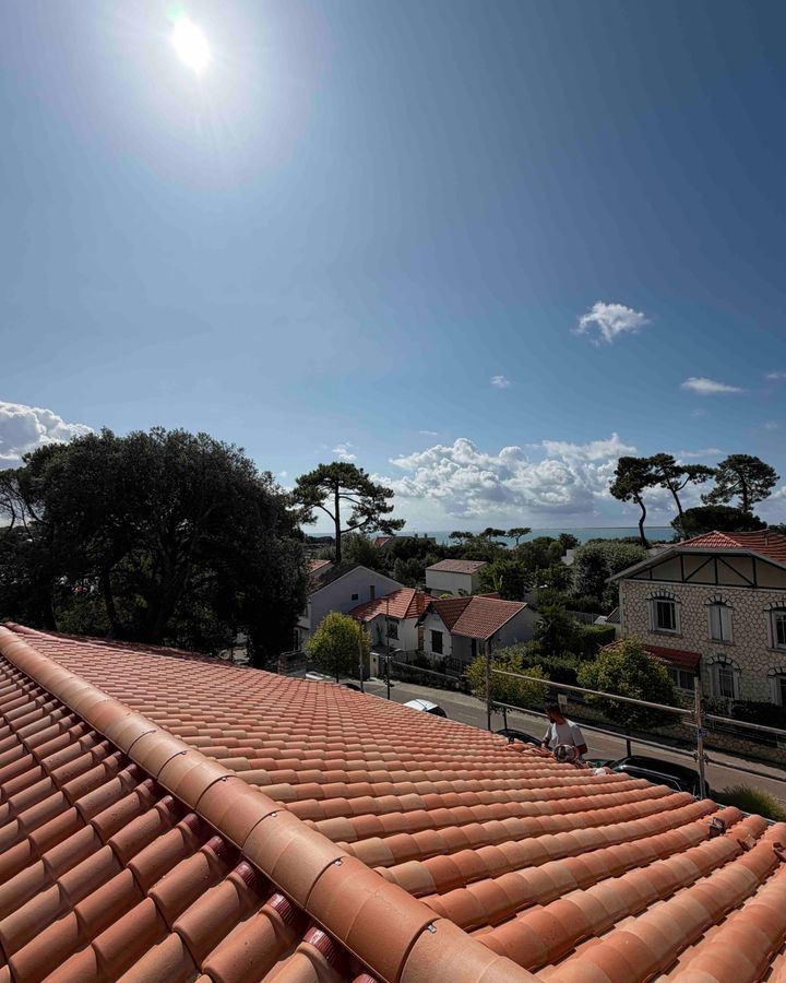 Toiture en tuiles canal refaite à neuf, avec des villas, des pins et la mer au loin