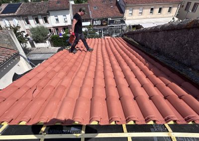 Technicien en réparation de toiture en tuiles rouges à La Rochelle.