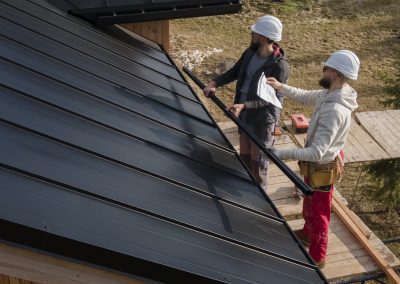 Travailleurs installant une toiture en métal sur une maison en construction.