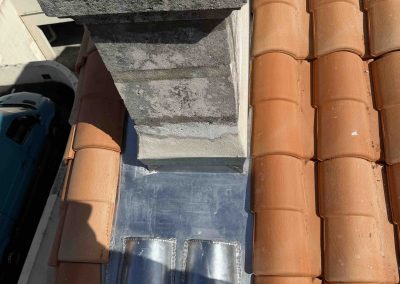 Solin en zinc soudé réalisé autour d'une souche de cheminée sur une toiture en tuiles
